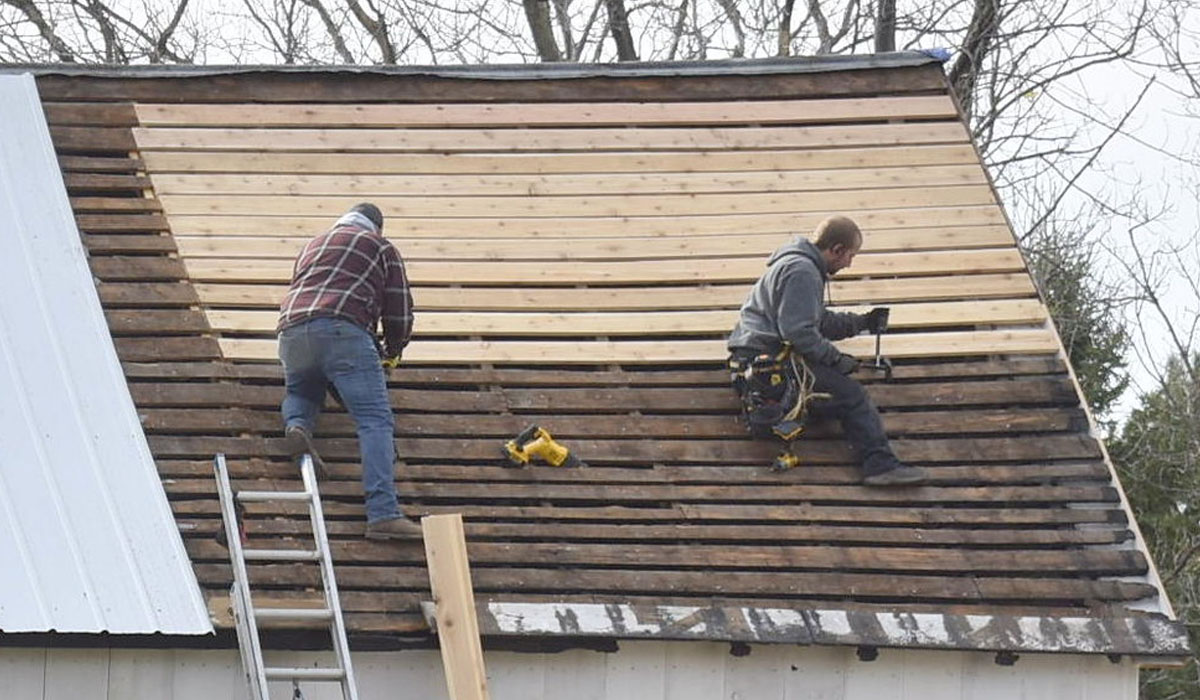 two roofers working on an unfinished roof in the cold weather